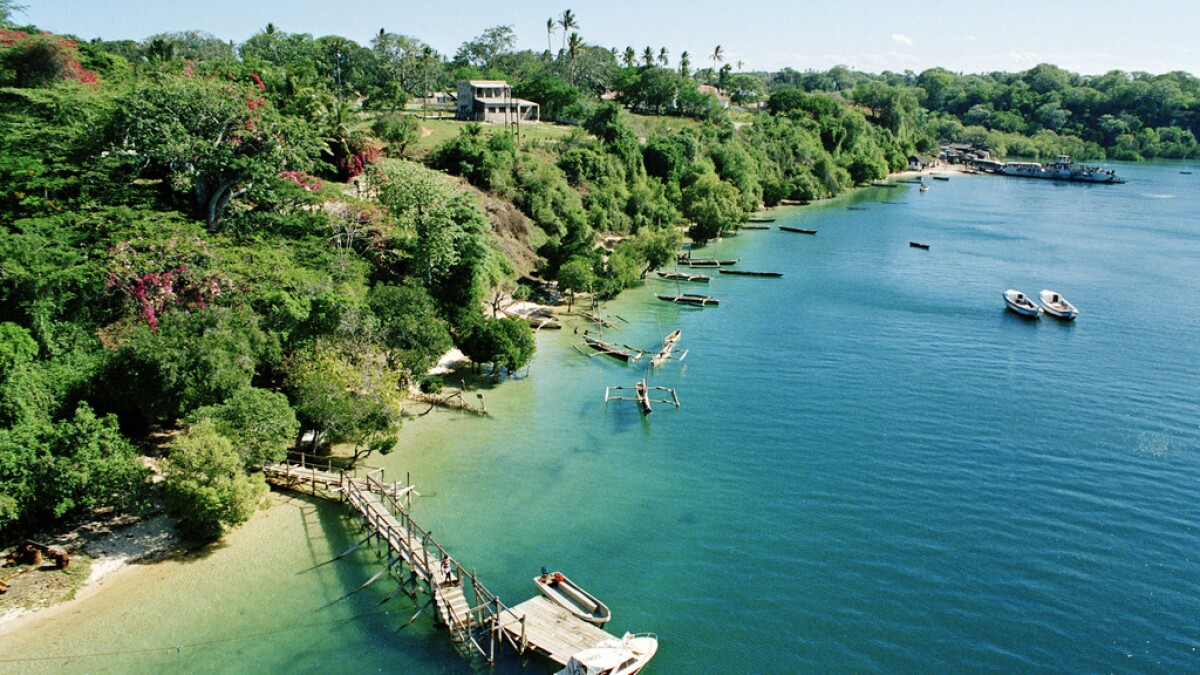 Ready for a day's work at sea, a small fleet of boats hugs the shoreline of a fishing village in the district of Kilifi. Fishing is important to the local economy. To the right is a ferry, which transports passengers from Mombasa Island to the Kenyan mainland.